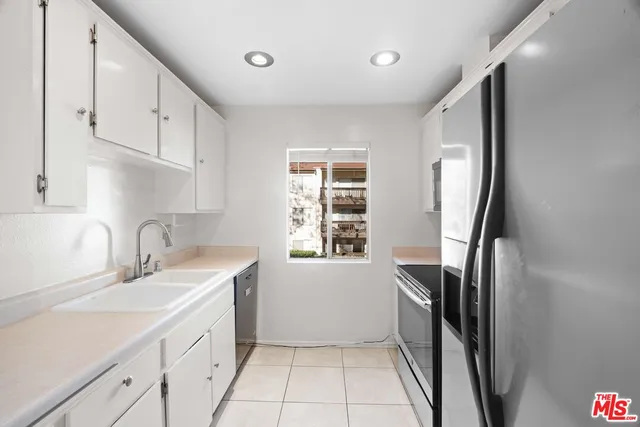 a kitchen with white cabinets and refrigerator