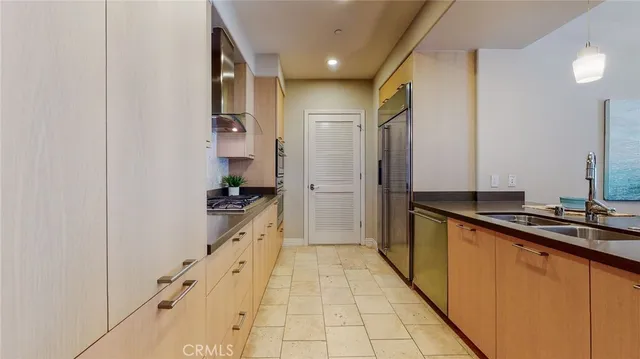 a large white kitchen with stainless steel appliances a sink and cabinets