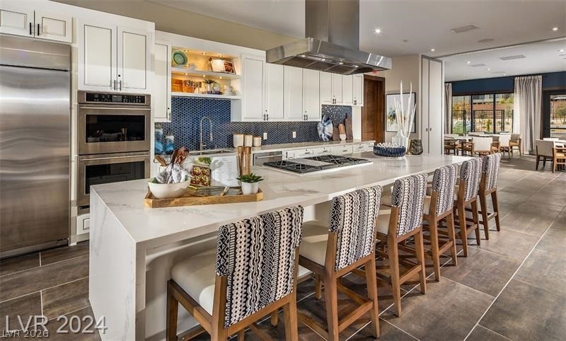 4246 Swift Street Las Vegas, NV 89135 - Photo 62 of 71 Kitchen featuring a breakfast bar area, stainless steel appliances, white cabinets, island exhaust hood, and open shelves