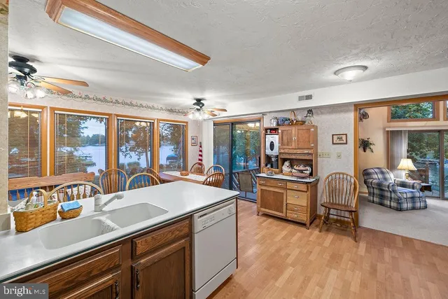a room with stainless steel appliances furniture a large window and a chandelier