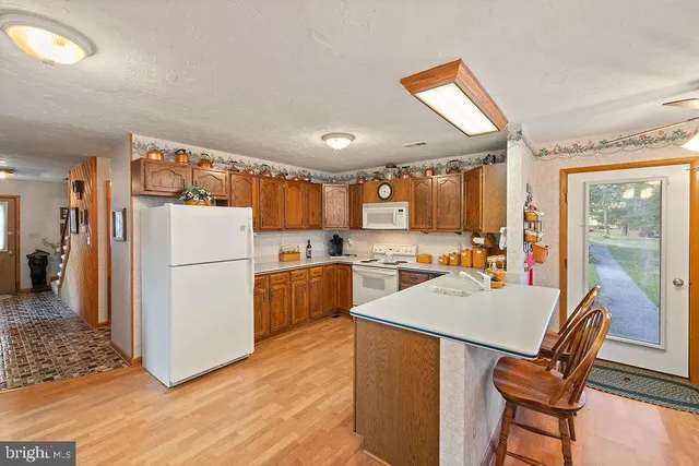 a kitchen with a refrigerator a stove a sink dishwasher with a dining table and chairs