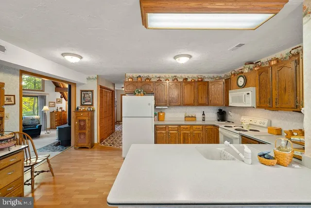 a kitchen with a refrigerator a stove a sink dishwasher and a dining table with wooden floor