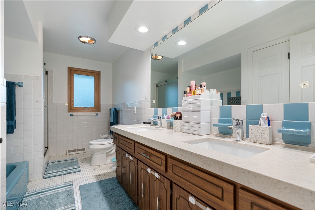 594 Long Ridge Drive Independence, OH 44131 - Photo 16 of 36 Full bath with tile patterned flooring, toilet, tile walls, double vanity, and a shower with door