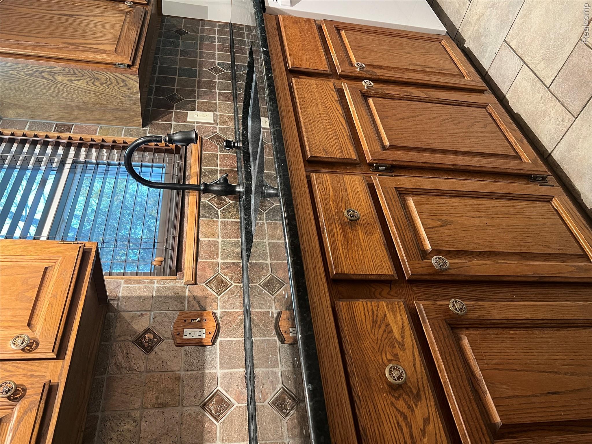 36795 Greenbush Road Wayne, MI 48184 - Photo 5 of 61 Kitchen with brown cabinetry, backsplash, dark stone counters, light tile patterned floors, and dishwasher