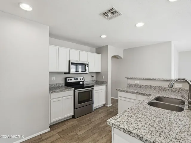 a view of kitchen with stainless steel appliances granite countertop refrigerator stove top oven and cabinets