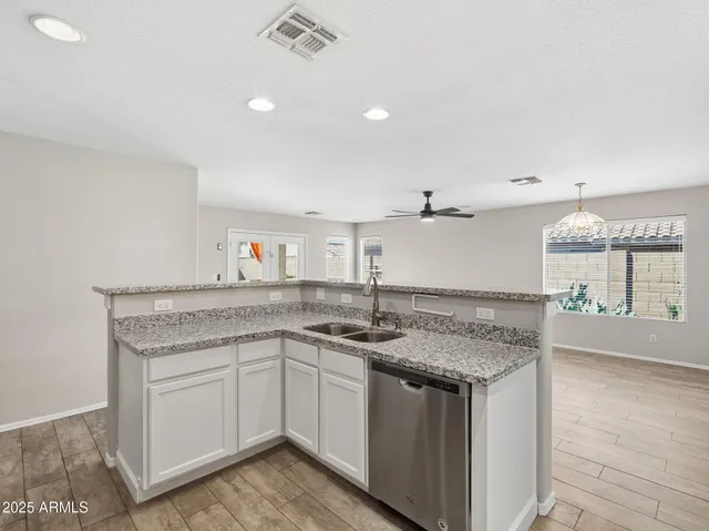 a kitchen with granite countertop a sink stainless steel appliances and white cabinets