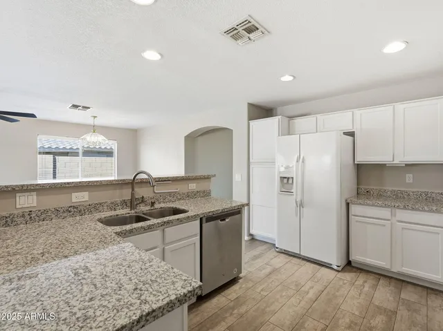 a kitchen with granite countertop white cabinets and stainless steel appliances