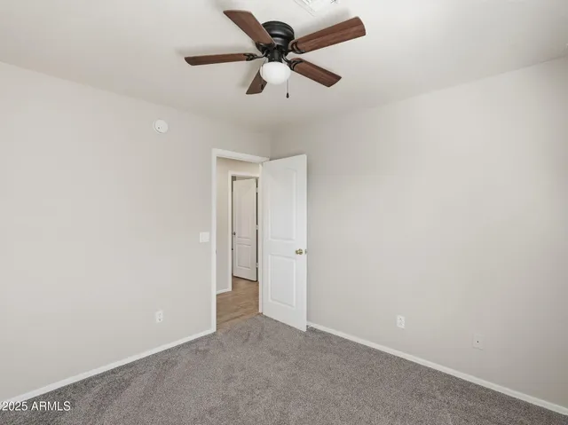an empty room with a ceiling fan and a window