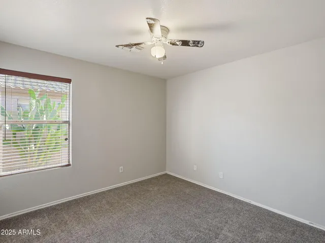 an empty room with a ceiling fan and carpet