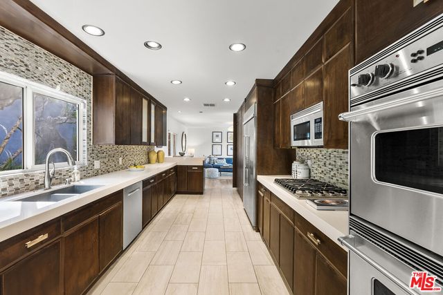 a large kitchen with stainless steel appliances granite countertop a stove a sink and a microwave