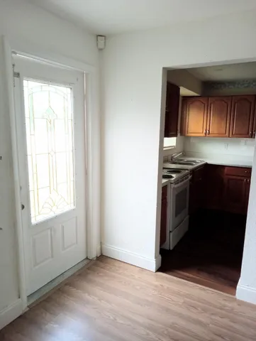 an empty room with wooden floor cabinet and a window