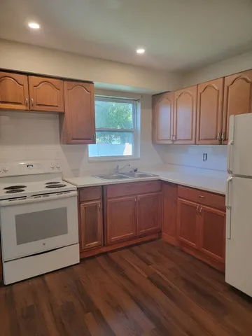 a kitchen with granite countertop wooden floors and white stainless steel appliances