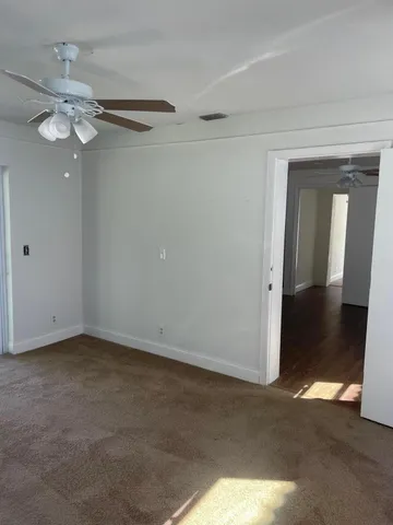 an empty room with windows and fan
