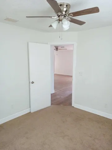 an empty room with a fan & a ceiling fan