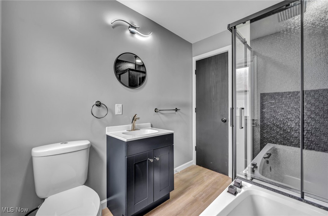 20202 Sumpter Road Cleveland, OH 44128 - Photo 19 of 46 Bathroom featuring light wood-style floors, vanity, and bath / shower combo with glass door
