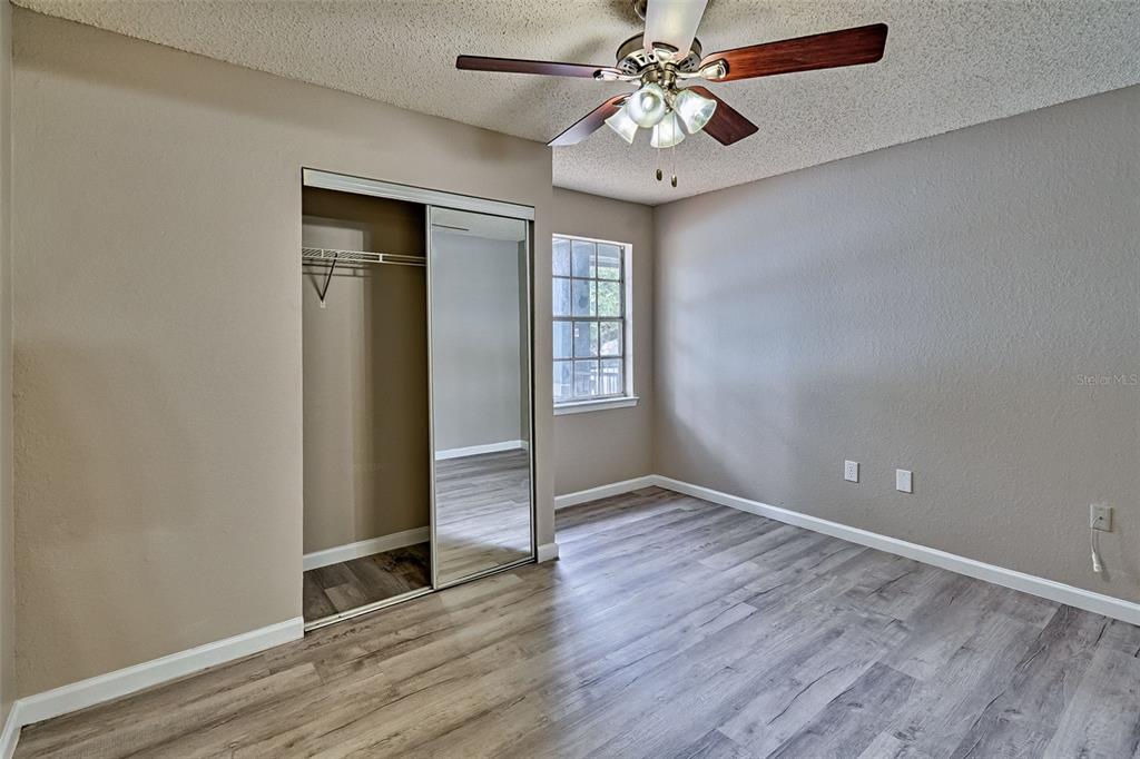 3705 Southwest 27th Street, Unit 926 Gainesville, FL 32608 - Photo 23 of 39 an empty room with wooden floor chandelier fan and closet area