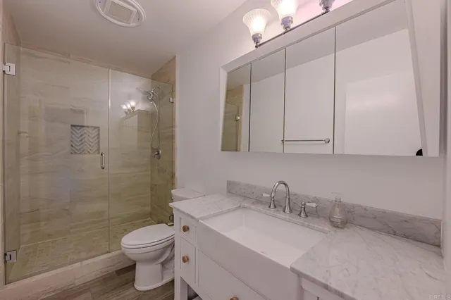 a bathroom with a granite countertop sink a toilet and shower