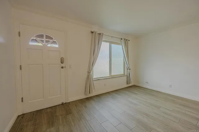a view of an empty room with wooden floor and a window