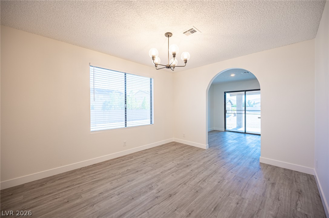 7041 North Decatur Boulevard Las Vegas, NV 89131 - Photo 11 of 33 A refined ceiling light fixture illuminates the space with subtle grace, complementing the elegant flooring and inviting arched entryway.