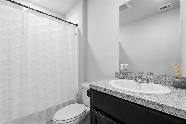 a bathroom with a granite countertop sink toilet and a mirror