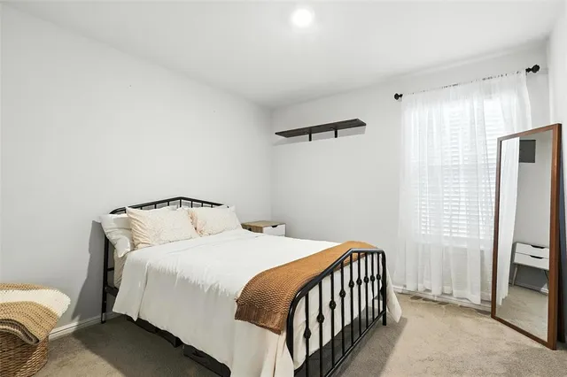 a bedroom with a bed and a flat tv screen on a dresser