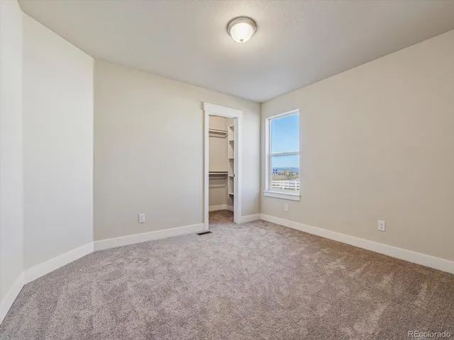 a view of an empty room with closet and a window