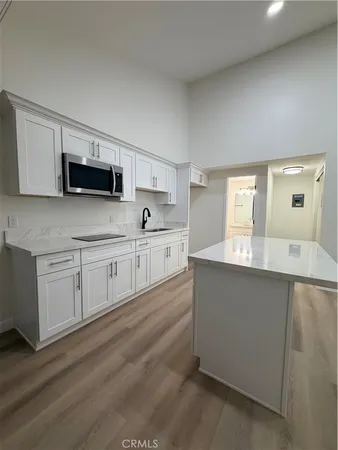 a kitchen with granite countertop white cabinets and black stainless steel appliances
