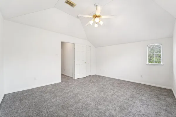 an empty room with chandelier fan and closet