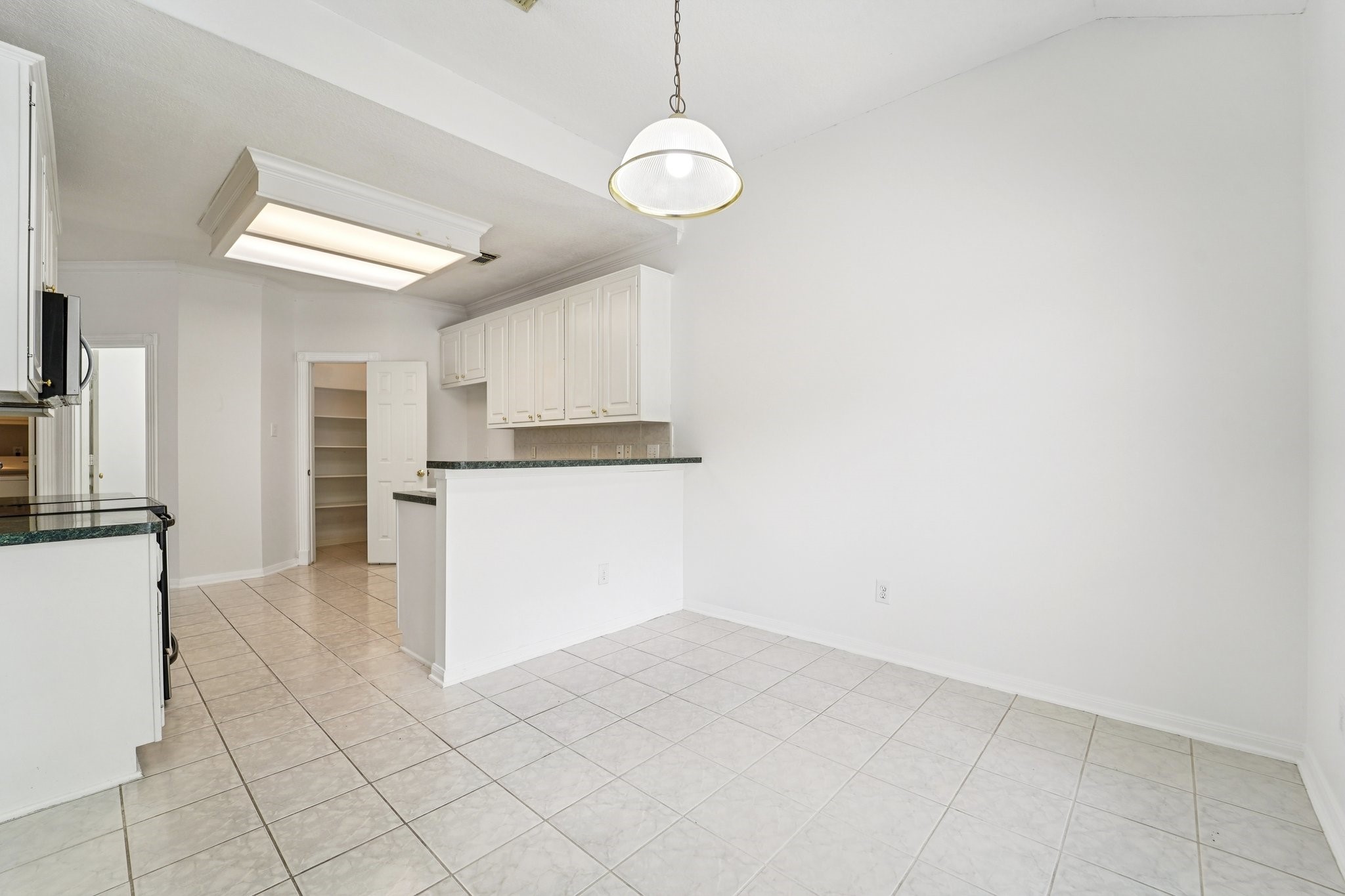 14420 Walters Road, Unit 55 Houston, TX 77014 - Photo 10 of 35 This photo showcases a bright, open kitchen and dining area with white cabinetry, tiled flooring, and a hanging light fixture. The space features ample storage and a modern layout, perfect for family gatherings.