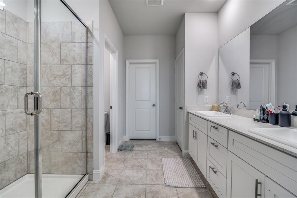 1069 Norias Drive Forney, TX 75126 - Photo 19 of 36 a spacious bathroom with a granite countertop sink a mirror and a shower