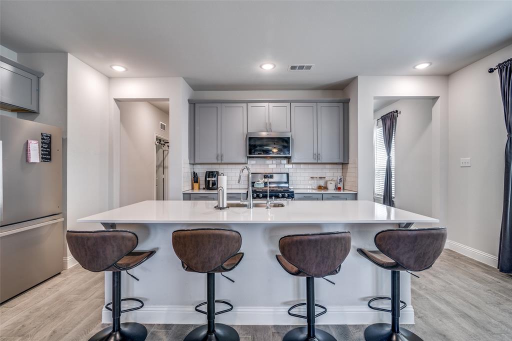 1069 Norias Drive Forney, TX 75126 - Photo 9 of 36 a kitchen with stainless steel appliances granite countertop a refrigerator a stove a sink and chairs with wooden floor