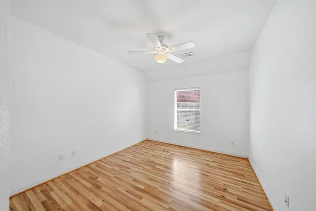 an empty room with a window and ceiling fan