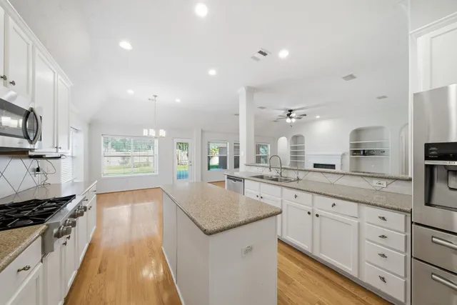a large kitchen with stainless steel appliances granite countertop a lot of counter space and wooden floors