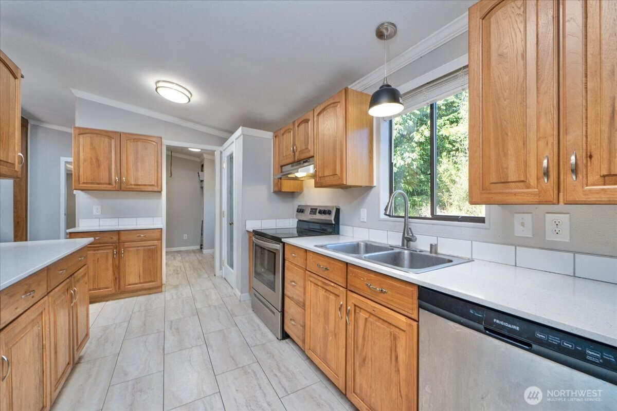 331 Frontier Road Grapeview, WA 98546 - Photo 14 of 39 a kitchen with stainless steel appliances wooden cabinets a sink and a large window