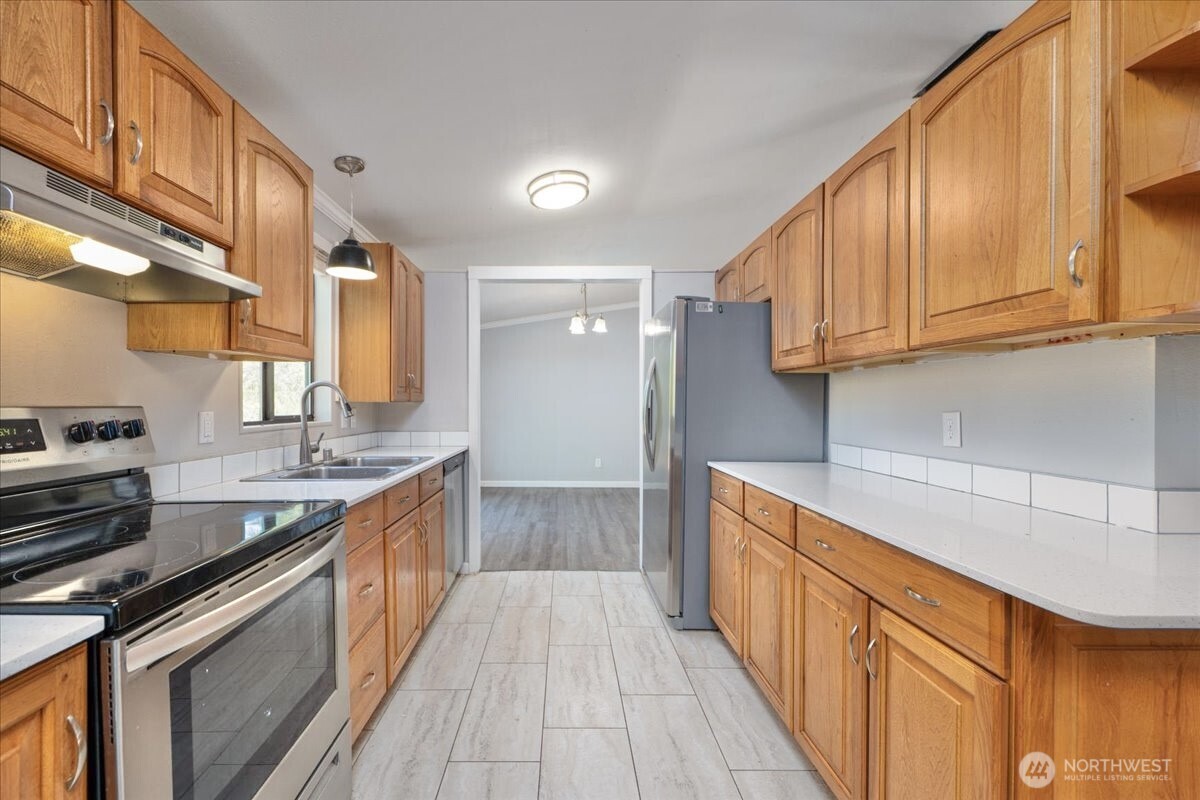 331 Frontier Road Grapeview, WA 98546 - Photo 17 of 39 a kitchen with stainless steel appliances granite countertop a sink and wooden cabinets