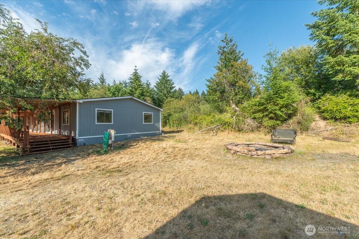 331 Frontier Road Grapeview, WA 98546 - Photo 35 of 39 a backyard of a house with large trees and wooden fence