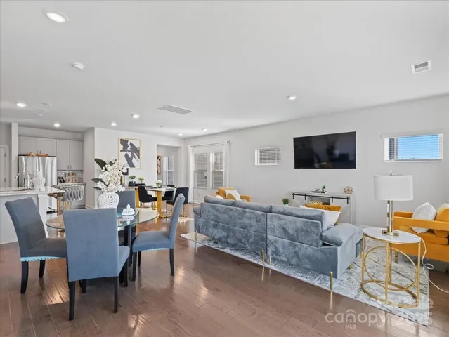 a living room with furniture a flat screen tv and kitchen view