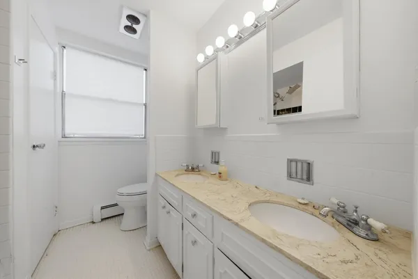 a bathroom with a granite countertop double vanity sink a mirror and a toilet