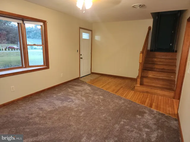 a view of an empty room with wooden floor and windows