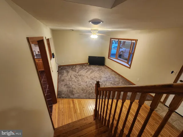 a view of a hallway to a livingroom with wooden floor and staircase