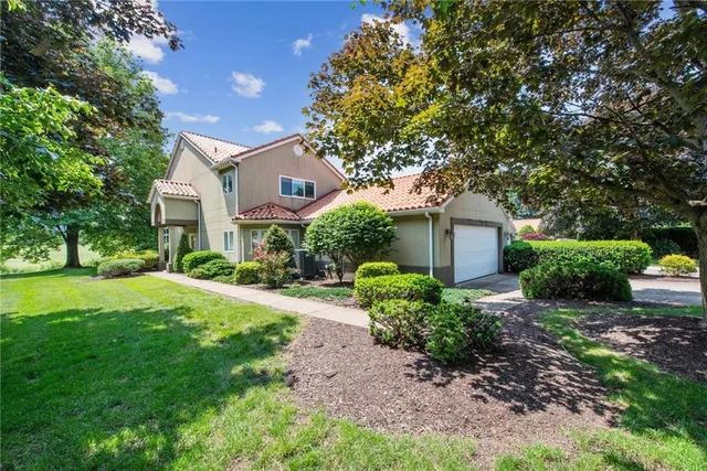 a front view of a house with a yard and shrubs