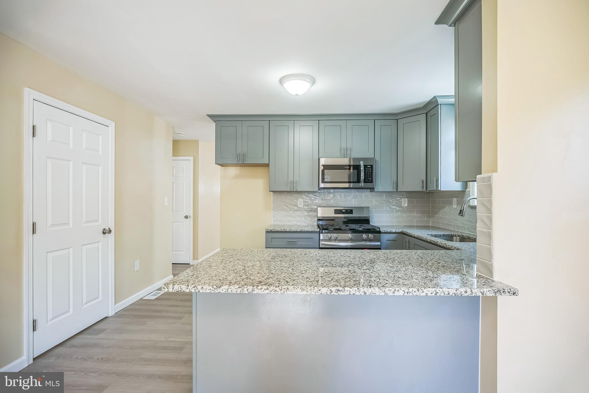 208 Hooker Street Riverside, NJ 08075 - Photo 7 of 25 a kitchen with granite countertop a stove top oven a sink a refrigerator and white cabinets