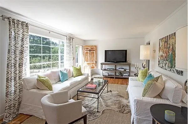 a living room with furniture a flat screen tv and a large window