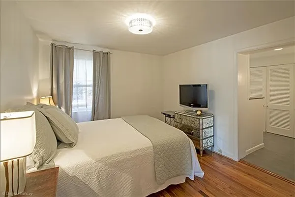 a bedroom with a bed a flat screen tv and a window