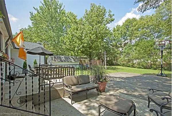 a view of a patio with couches table and chairs and wooden fence