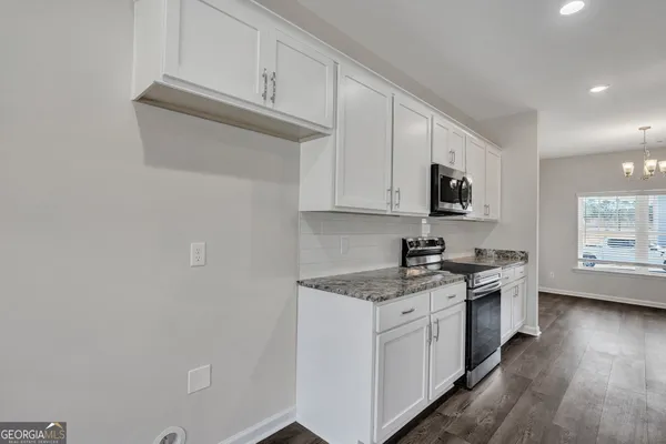 a kitchen with granite countertop white cabinets and white appliances