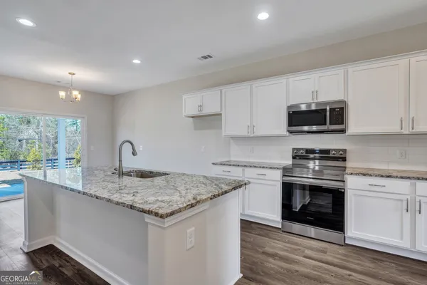 a kitchen with granite countertop a stove sink and microwave