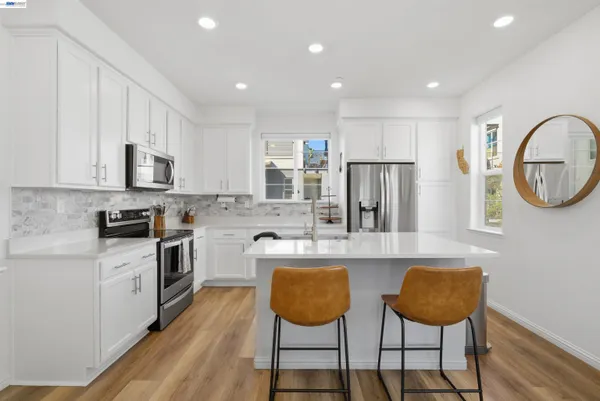 a kitchen with stainless steel appliances granite countertop a stove a sink dishwasher a dining table and chairs with wooden floor