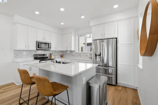 a kitchen with stainless steel appliances granite countertop a refrigerator a stove a sink and a microwave