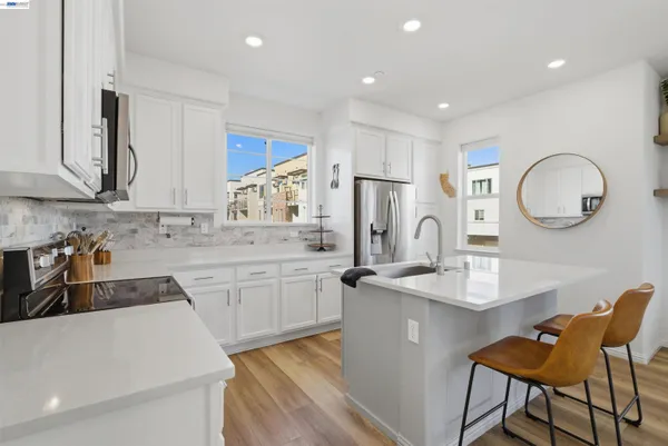 a kitchen with stainless steel appliances granite countertop a sink a stove a refrigerator cabinets and chairs